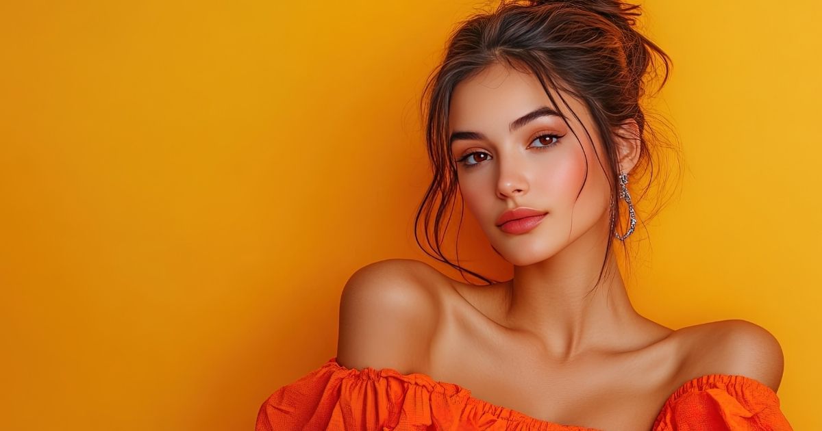Blog-Totality Medispa-Cheek Filler vs. Jawline Filler Where Should You Start Woman in an orange off-shoulder top against an orange background.
